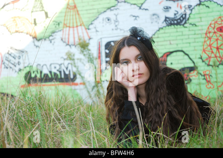 Giovane donna in posa di fronte del muro di graffiti Foto Stock