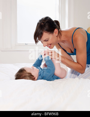 Madre sorridente al Bambino giacente sul letto Foto Stock