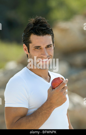 Un maschio latino tenendo un Apple sorridenti Foto Stock