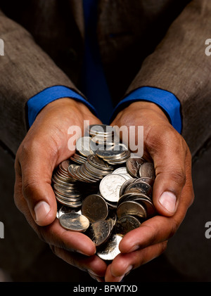 Uomo d affari con manciata di monete Foto Stock