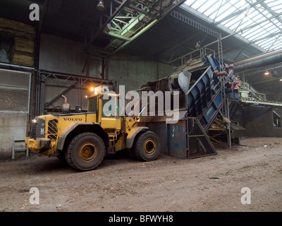 Volvo grande pala di carico di dumping di rifiuti organici in trinciatrice a impianto di compostaggio Foto Stock