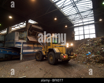 La pala di carico materiale naturale rifiuti in grandi shredder in impianto di compostaggio, dove saranno elaborati per diventare la biomassa Foto Stock