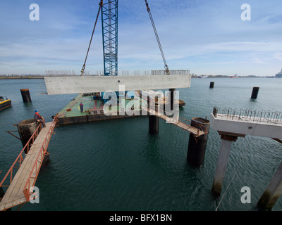 Grandi gru galleggiante il sollevamento di un blocco di calcestruzzo in posizione durante la creazione di una stazione docking pier per una grande nave di petrolio. Foto Stock