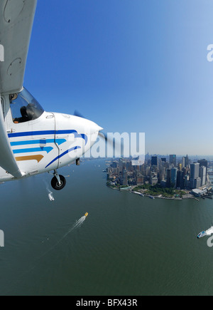 Un aereo leggero Cessna 172 volando sopra la parte inferiore di Manhattan e del fiume Hudson, New York City, Stati Uniti d'America Foto Stock