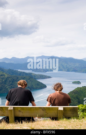 Gli uomini seduti su un banco di lavoro guardando giù su Picton e il Marlborough Sounds, Isola del Sud, Nuova Zelanda Foto Stock