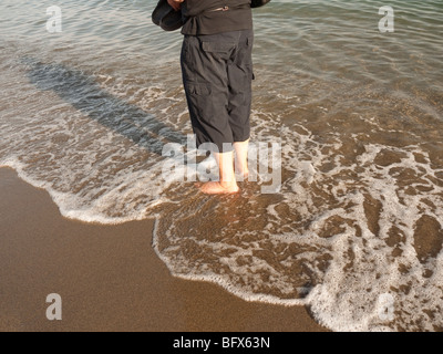 L'uomo una spiaggia permanente al bordo delle acque in Torremolinos Spagna Foto Stock