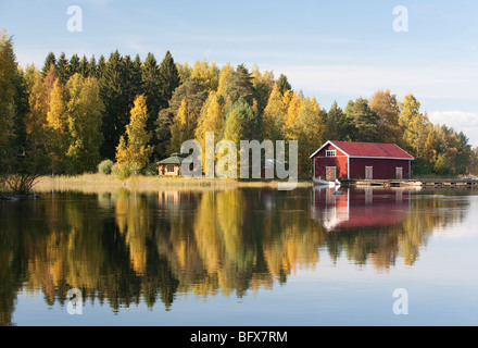 Il Boathouse rosso e una piccola sauna all'altro lato del fiume , Finlandia Foto Stock