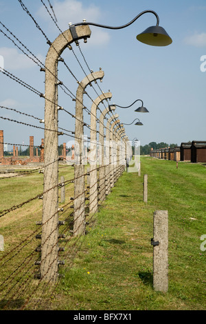 Recinzioni perimetrali / Birkenau (Auschwitz II Birkenau) nazista di morte nel campo di Oswiecim, Polonia, & ciminiere in laterizio da case a castello dietro Foto Stock