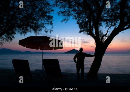 Grecia. Zante. Zante.ottobre. Uomo in vacanza che guarda l'alba sul mare a Keri Bay, affacciato sull'isola di Marathonisi. Alberi di Tamarisk. Foto Stock