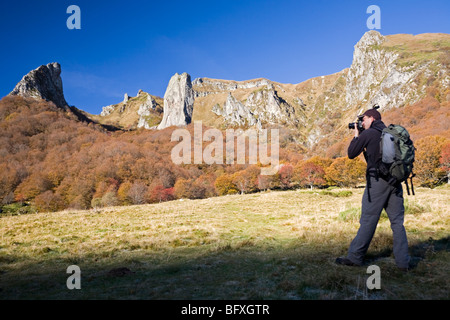 Un escursionista fotografare la valle di Chaudefour, in autunno (Francia). Randonneur photographiant la vallée de Chaudefour, en automne. Foto Stock