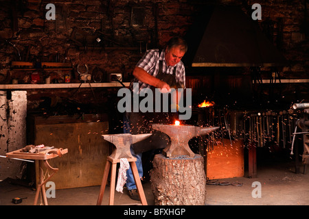 Un fabbro al lavoro nel villaggio di Cockington, Devon Foto Stock