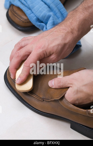 Un uomo la lucidatura di un paio di scarpe Foto Stock