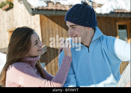 Giovane al di fuori di Ski lodge, giovane donna applicando LIP BALM di giovane Foto Stock