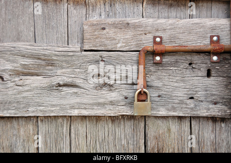 Dettaglio di un lucchetto e un vecchio bold di una porta di legno Foto Stock