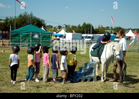 Nel bilancio annuale Gascogne Expo fiera agricola in Auch bambini piccoli la linea fino a prendere giri alla seduta su un pony Foto Stock