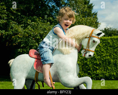 Un giovane ragazzo giocando su un cavallo a dondolo Foto Stock