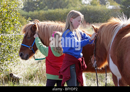 Due giovani ragazze haltering loro pony Foto Stock
