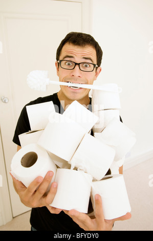 Uomo con spazzola per WC e rotoli di carta igienica Foto Stock