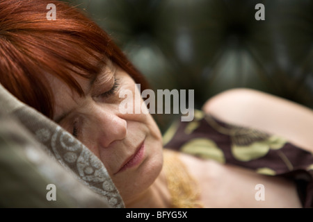 Signora matura che dorme sul divano Foto Stock