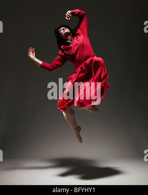 Donna in abito rosso ballando sotto luce Foto Stock