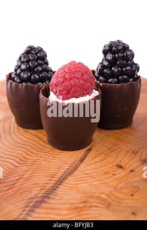 Tre mini-tazza di cioccolato con panna e lamponi e more. Foto Stock