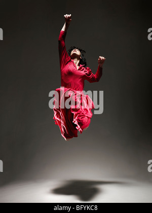 Donna in abito rosso ballando sotto luce Foto Stock