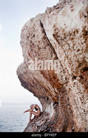 Donna seduta sulle rocce al cliffs Foto Stock