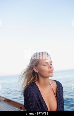 Donna con gli occhi chiusi su una barca a vela Foto Stock