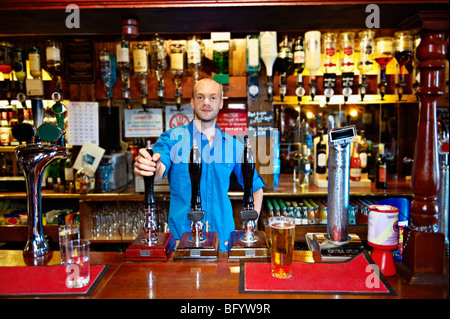 Barman in piedi dietro il bar in pub Foto Stock