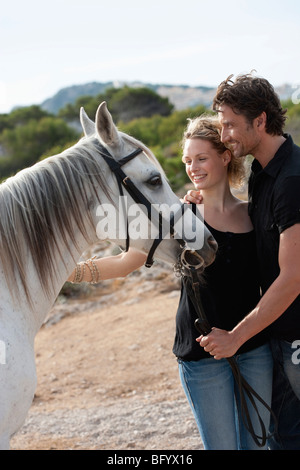 Coppia sorridente holding cavallo Foto Stock