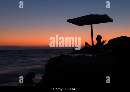 Zante. Zante. All'alba. Uomo in vacanza a guardare il tramonto sul mare dal promontorio tra Banana beach e Ag. Nikolaou (Agios Nikolaos) Foto Stock