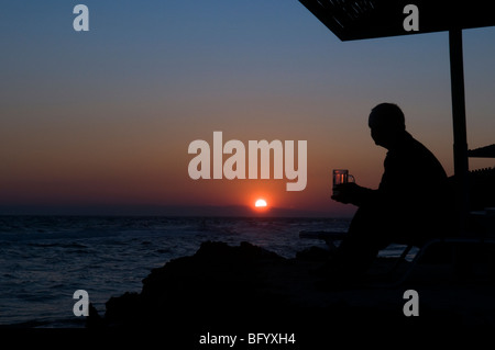 Zante. Zante. All'alba. Uomo in vacanza a guardare il tramonto sul mare dal promontorio tra Banana beach e Ag. Nikolaou (Agios Nikolaos) Foto Stock