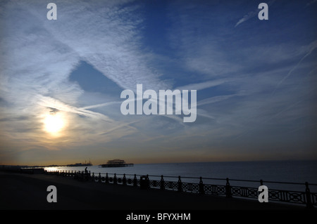 Alba sul lungomare di Brighton con jet striature nel cielo e il molo di ponente profilarsi in lontananza. Foto Stock