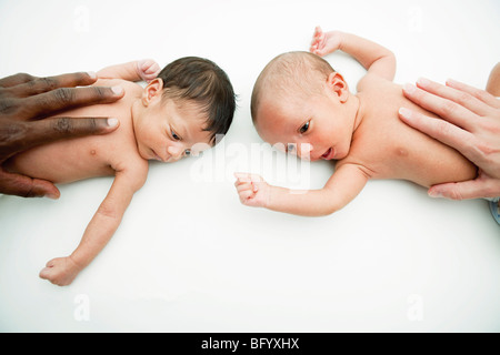 Multirazziale mani su bimbo di stomaco Foto Stock