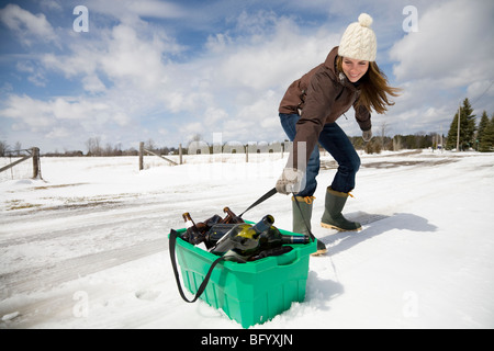 Donna trascinando il riciclaggio nella neve Foto Stock