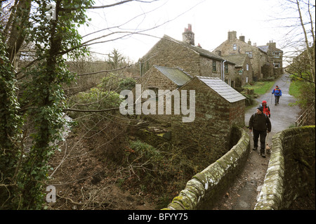 Walkers attraversando un ponte sul torrente a Edale nella speranza Valley vicino a Castleton Derbyshire Peak District Foto Stock