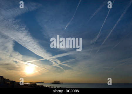 Alba sul lungomare di Brighton con jet striature nel cielo e il molo di ponente profilarsi in lontananza. Foto Stock