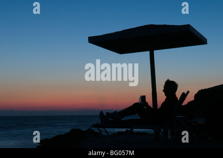 Zante. Zante. All'alba. Uomo in vacanza a guardare il tramonto sul mare dal promontorio tra Banana beach e Ag. Nikolaou (Agios Nikolaos) Foto Stock