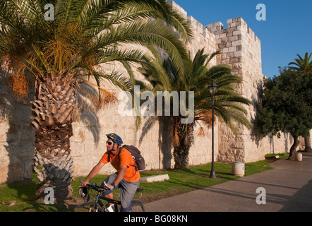 Ciclista in sella alle mura della città di Gerusalemme la città vecchia vicino alla Porta di Jaffa Foto Stock