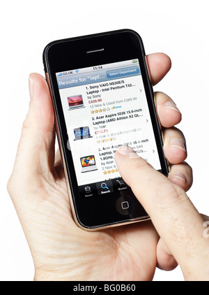 Uomo che tiene in mano un vecchio iPhone utilizzando l'app Amazon shopping su uno smartphone smartphone cellulare Foto Stock