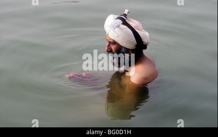 Un uomo Sikh prega nelle prime ore del mattino nelle acque che circondano il tempio d'oro di Amritsar, India Foto Stock