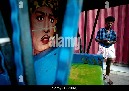 Un rickshaw pilota si prende una pausa per un fumo. La pittura in rickshaw è quello di un ex capo Ministro (equivalente di un governatore DEGLI STATI UNITI) del Sud lo stato indiano del Tamil Nadu, M.G. Ramachandran, a Madurai, India Foto Stock