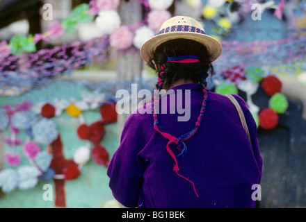 Il rispetto è pagato e i membri della famiglia onorato da una donna che ha dato marcatori e lapidi che sono state decorate per il Giorno dei Morti festival a Todos Santos, Guatemala Foto Stock