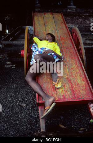 Un portiere dorme sul suo carro di Chennai, India Foto Stock