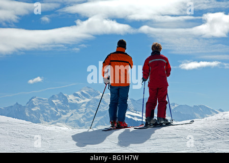 Due gli sciatori guardando attraverso la coperta di neve sulle Alpi francesi verso il Mont Blanc di picco, Morzine Avoriaz Alta Savoia, Francia Foto Stock