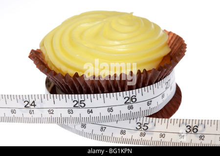 Giallo cupcake con glassa smerigliato schiacciato dal nastro di misurazione con misure metriche e imperiali Foto Stock