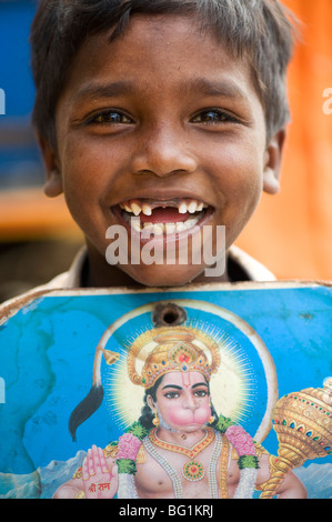 Povero indiano street boy sorridente con un'immagine della divinità Indù hanuman Foto Stock