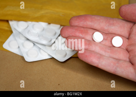 Man mano che regge due compresse da ordine di posta delle strisce di codeina base antidolorifici in un sacchetto di jiffy Foto Stock