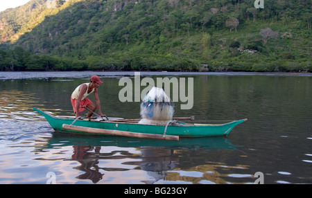 Un uomo di pesce sulla sua outrigger fatti in casa in canoa Coron Island. Foto Stock