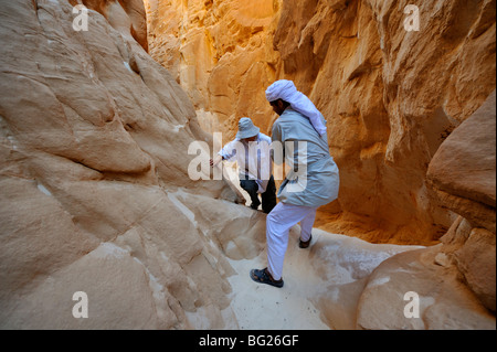 Guida beduina aiutando turista in molto strette Abu Hamata Canyon, Sud nel deserto del Sinai, Egitto Foto Stock